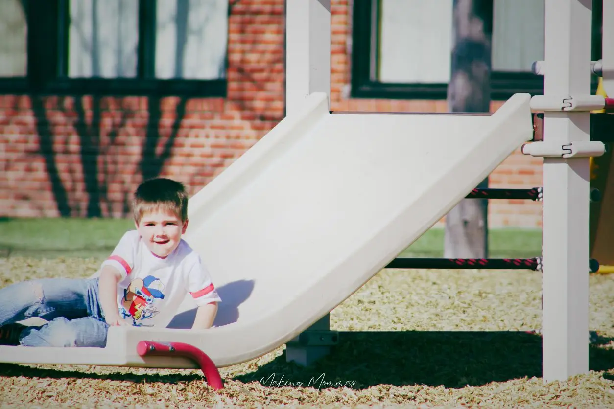 image of a little boy sliding down the slide