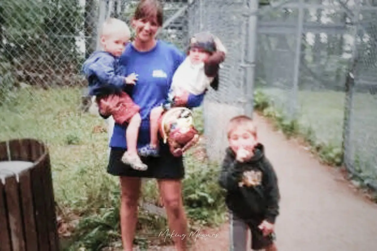 image of a mom holding two small boys and a third boy standing next to her
