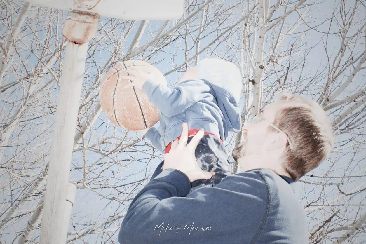 image of a little boy being lifted up by a man to play basketball