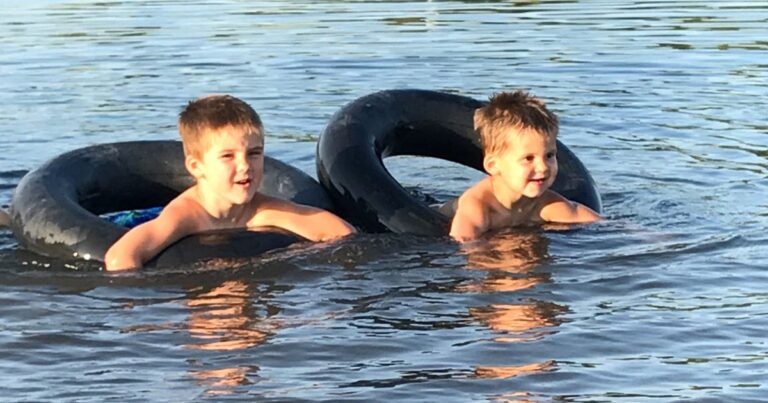 image of two boys swimming in tire tubes