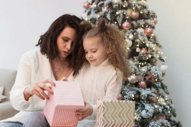 image of a mom and little girl opening a Christmas gift