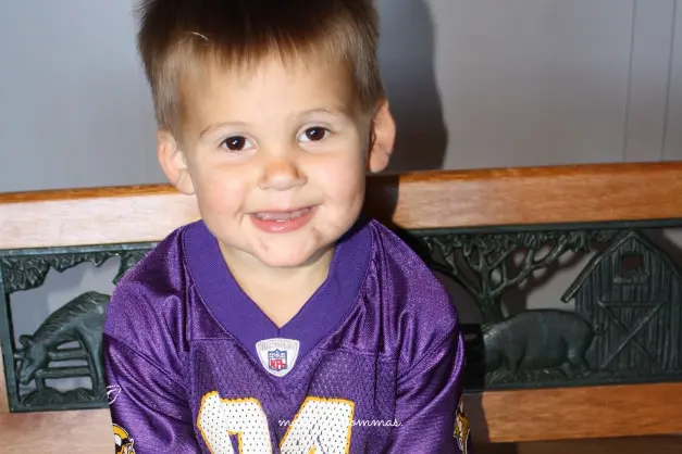 image of toddler in vikings jersey sitting on a bench