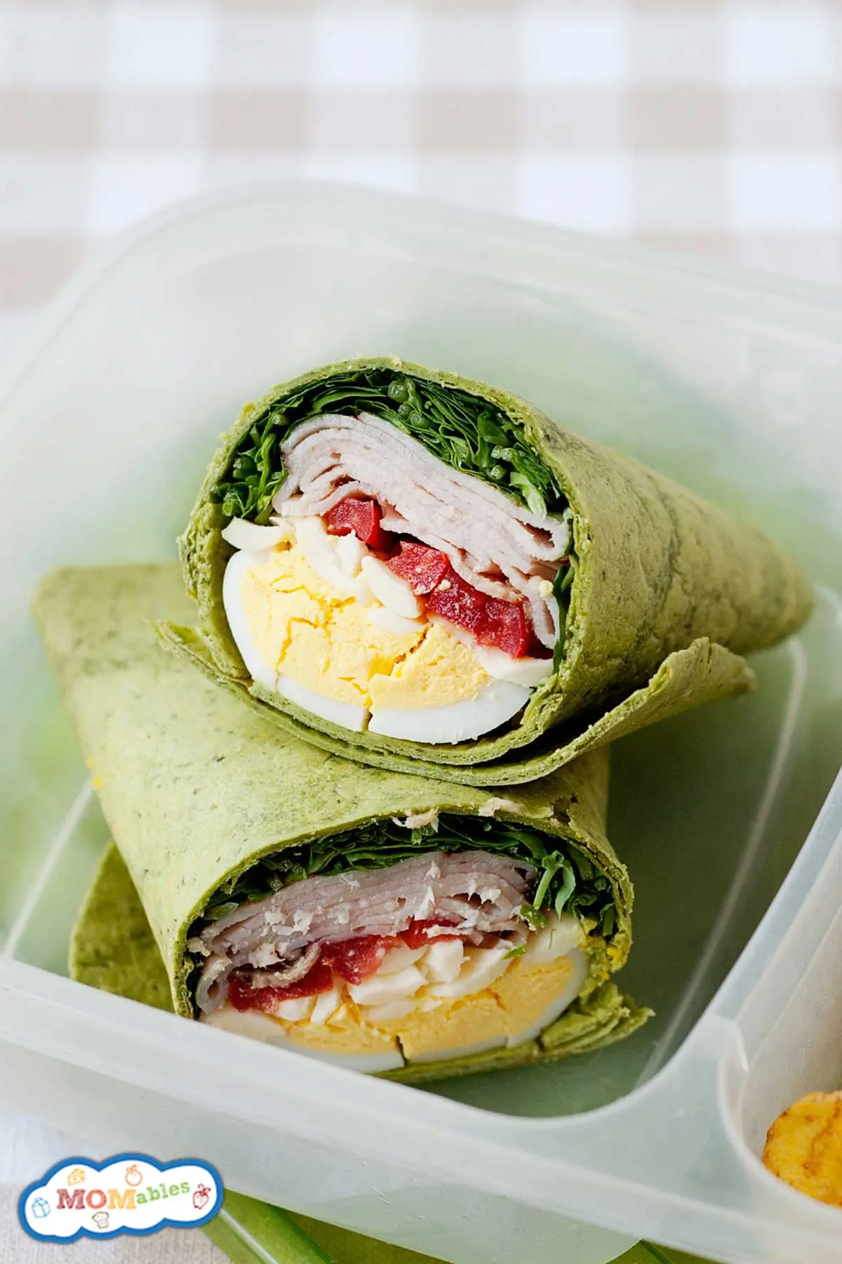 image of a turkey club wrap with lettuce, tomatoes, and boiled eggs