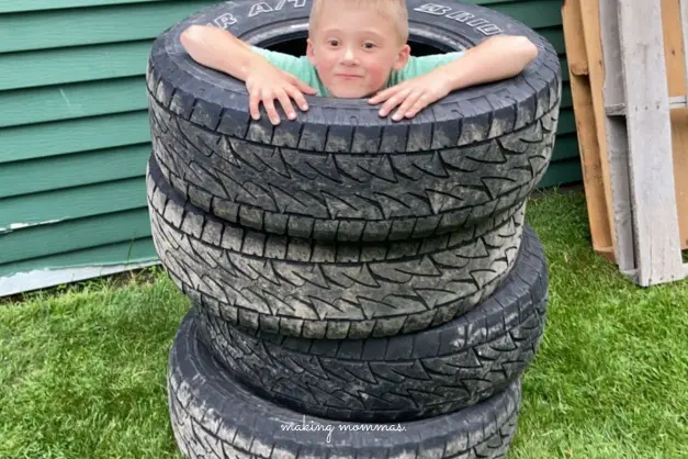 image of a boy playing inside a stack of tires