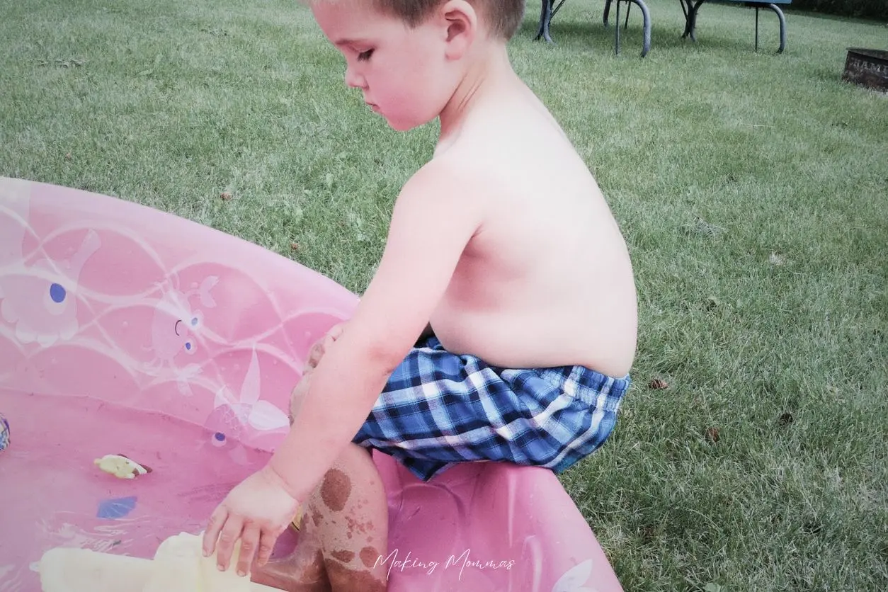 image of a little boy playing in a pink pool in the yard