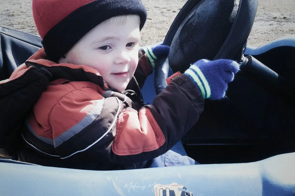 Image of a little boy driving a go cart in the fall.